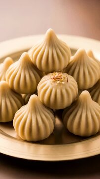 Woman garnishing modak with saffron strands on a gold plate for Ganesh Chaturthi. Indian traditional sweet dumpling dessert prepared for festive celebration. Vertical video