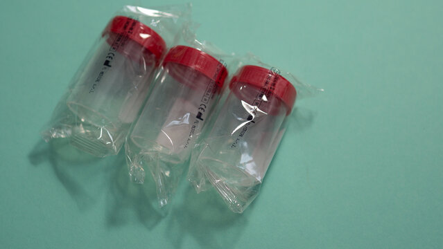 Sterile medical specimen containers in sealed packaging on blue background