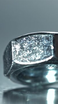 Closeup hex nut rotating and settling on reflective table, polished Filmed on a high-speed camera at 1000 fps.