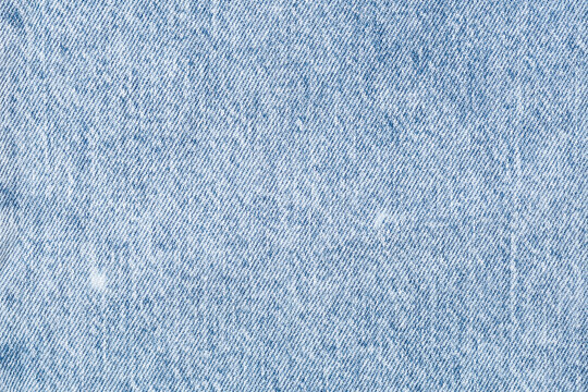 Macro pattern of light blue denim fabric texture with visible weave and soft washed effect background