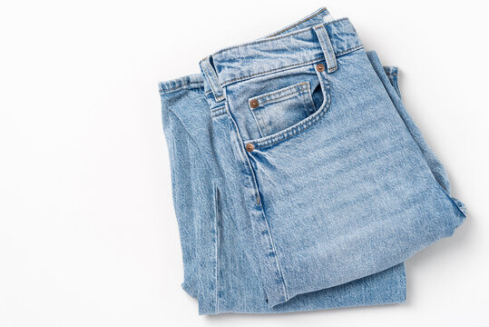 Top view of folded light blue denim jeans on white background, copy space