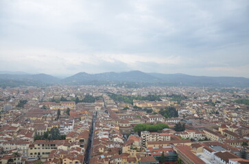Obraz premium Wide Panoramic View of Florence Rooftops and Tuscan Hills Under Cloudy Sky