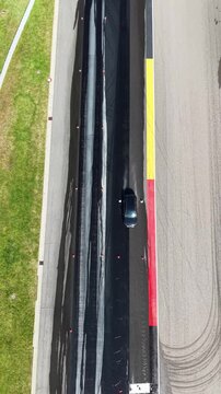Vertical Aerial View of Car on Race Track with Colorful Kerb