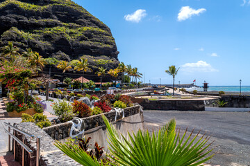 Tropical promenade with palm trees, flowers and volcanic cliffs in Puerto de Tazacorte on La Palma beside the Atlantic. © EKH-Pictures