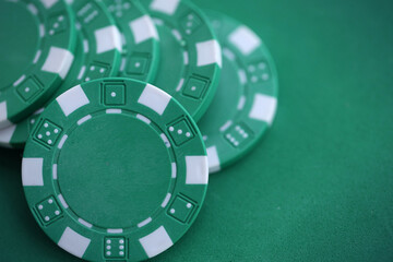 Naklejka premium Green casino poker chips on green gaming table close up. Few amount of green casino chips
