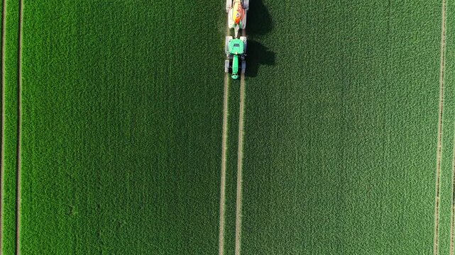 Vertical Aerial Top Down View of Crop Sprayer Tractor on Green Field