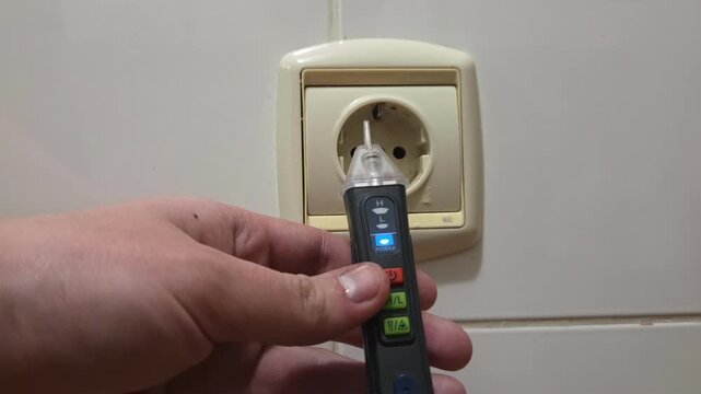 Handheld tracking shot of hand testing electrical outlet with non contact voltage tester in tiled bathroom interior