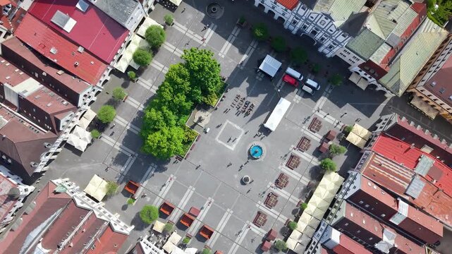 Cinematic aerial drone footage of Mari&aacute;nske N&aacute;mestie in the historic center of Žilina, Slovakia, featuring the Church of the Conversion of Saint Paul, surrounding architecture, urban square, rooftops,