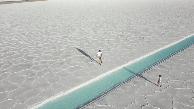 Aerial view of father and child playing football on white salt flats Salinas Jujuy Argentina