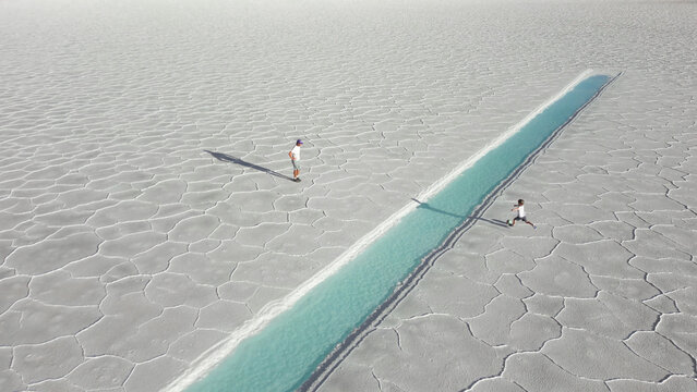 Aerial view of father and child playing soccer onwhite salt flats Salinas Jujuy Argentina