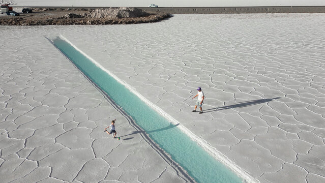 Aerial view of father and child playing football onwhite salt flats Salinas Jujuy Argentina