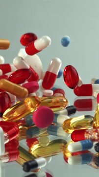 Mixed capsules and softgels swirling glass surface vibrant pharmacy Filmed on a high-speed camera at 1000 fps.