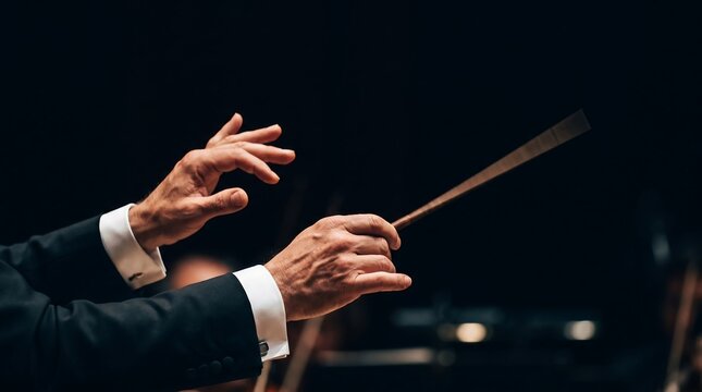 Close-up on orchestra conductor's hands gracefully leading musicians with a baton