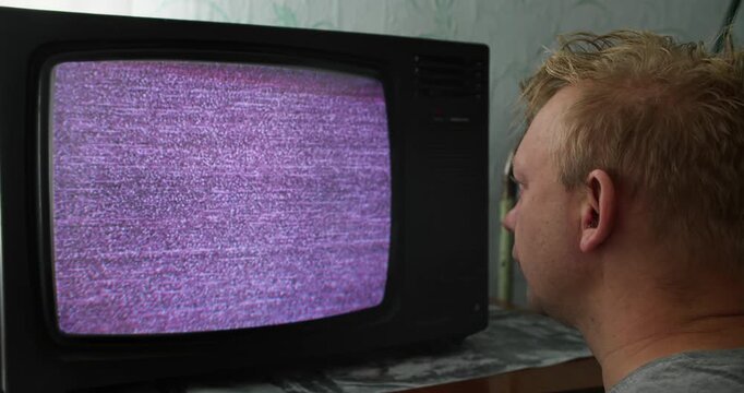Person fixated on CRT television static, seated close to the screen. Mindless viewing and visual overstimulation concept