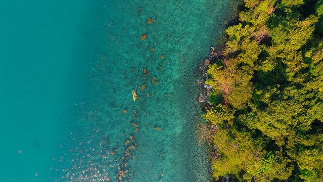 Kayaker paddling over clear turquoise water near lush tropical koh chang island