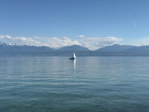 Single Boat Floating on the Calm Waters of a Scenic Swiss Lake With Alpine Mountains Beyond