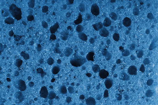 Macro, closeup of blue foam sponge texture with porous, spongy and bubbly surface pattern suitable for abstract background design. Foamed polyurethane material surface