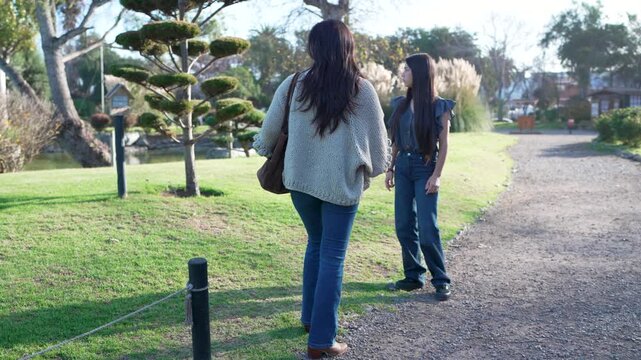 Young girl having a serious and difficult conversation with her mother while walking in a public park