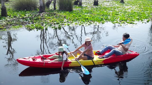 Happy Asian family parents and young daughter kayaking together in lake. Father, mother and child enjoy adventure travel nature active lifestyle paddling canoe during outdoor summer holiday vacation.