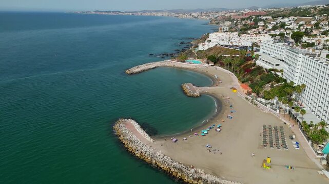 High angle view of Benalmadena coastline near Malaga, Spain. Scenic resort beach with blue sea waves, golden sand, beachfront luxury hotels, and holiday villas on the Costa del Sol.