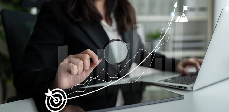 A businesswoman in a formal setting examines graphs and data trends to make informed decisions, highlighting the importance of analysis and strategy in the modern workspace. Ledger