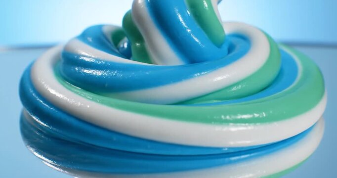 Blue and white striped toothpaste being squeezed onto a glass surface
