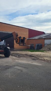 Side view of a yellow telehandler parked at a distribution facility, industrial vehicle profile, logistics transport gear. machinery design, commercial fleet, logistics infrastructure.