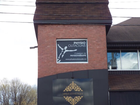 Gatineau, Quebec, Canada &ndash; April 21, 2026: A red brick building features window signage for "PHYSIO OUTAOUAIS" above a lower sign for "ONYX ESTH&Eacute;TIQUE" at 729 Boulevard Saint-Joseph #200.
