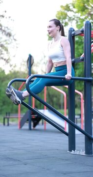 Athletic woman exercising on parallel bars at outdoor gym