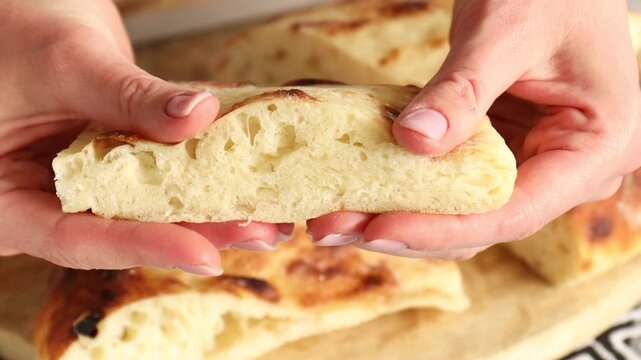 Woman with pieces of tasty flatbread at table, closeup