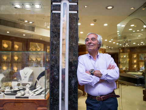 Confident jeweler standing in the doorway of an elegant jewelry store with arms crossed