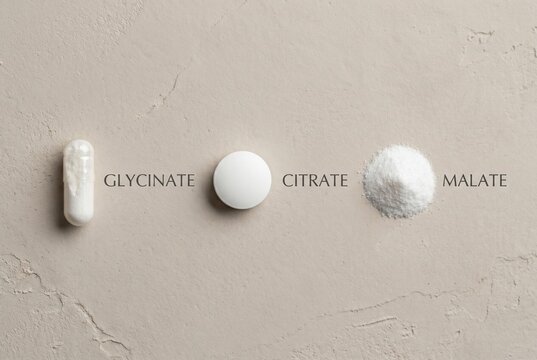 Comparison of magnesium supplement forms: glycinate capsule, citrate tablet, and malate powder. Minimalist flat lay infographic on a neutral textured background