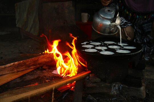 The traditional serabi cake making process uses an aluminum pan to pour the white batter into. The baking process is authentically done using a natural wood-burning stove.