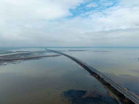 A high aerial view showing a long bridge spanning across the water in Jiujiang China on a cloudy day
