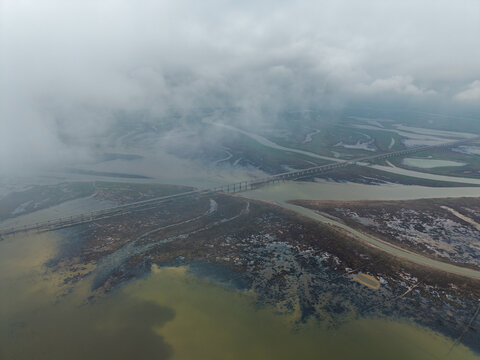 Aerial view showing the vast landscape and a long bridge spanning across the river in Jiujiang China under a cloudy sky