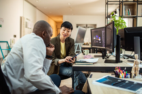 Coworkers reviewing mobile app design in modern office