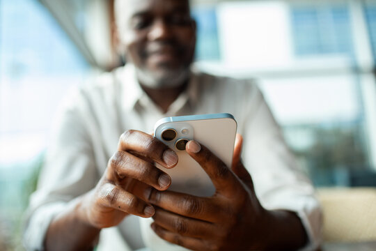 Mature man using smartphone indoors, close-up