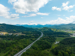 Fototapeta premium A high angle aerial view of a highway stretching through the green mountains and landscape of Wuyi Mountain in Fujian China