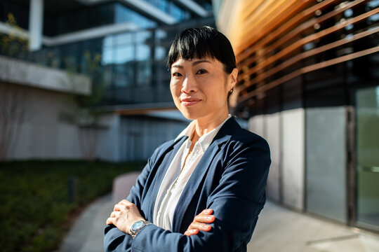 Confident businesswoman with arms crossed outside office