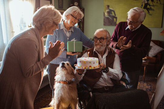 Senior friends celebrate birthday with cake at home