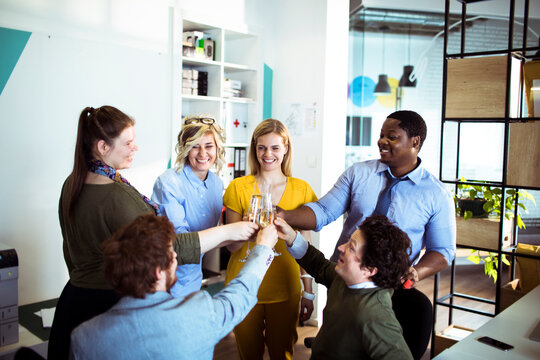 Happy coworkers toasting success in modern office