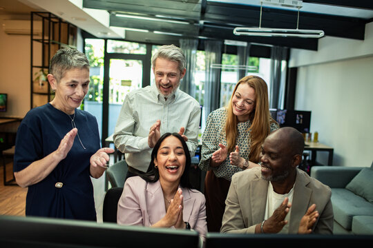 Smiling coworkers applauding a successful presentation in a modern office