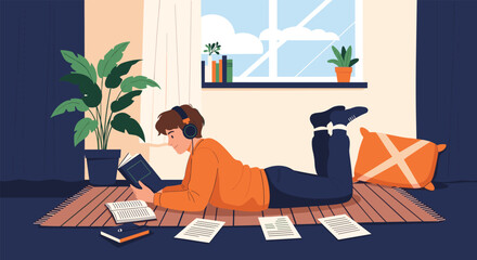 Fototapeta premium Young male student lying on a rug and studying with books, papers, and headphones in a cozy room with plants and a window.