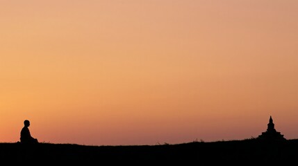 Fototapeta premium Buddhist monk meditating at sunset with temple
