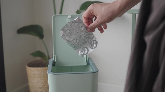Hand throwing away empty medication pack in a waste bin