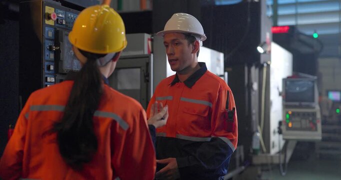 Technicians reviewing machine setup with clipboard in auto parts factory