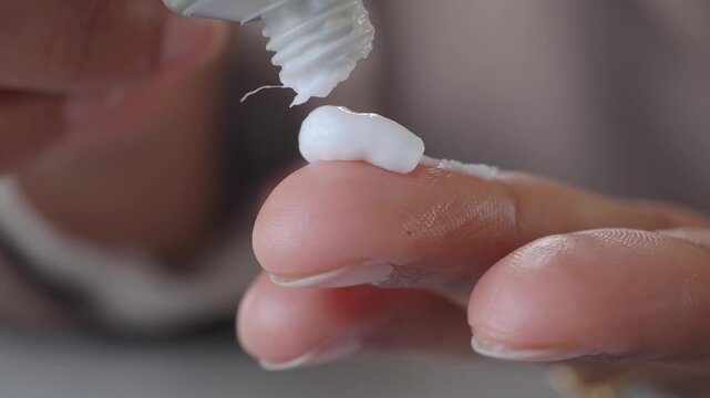 Applying cream on finger for skin care in home setting