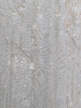 Close-up of a brushed concrete surface featuring a distinct broom finish texture, linear grooves, fine scratches, and a neutral beige tone ideal for industrial architectural backgrounds.