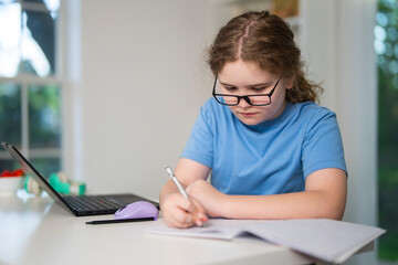 Fototapeta premium Student studies at home today. Student learner uses headphones online. Focused student completes homework daily. Happy student enjoys virtual class.