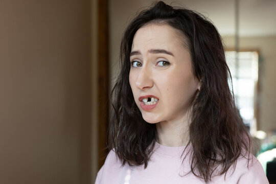 Mature woman experiences emotions about missing front tooth in indoor space during dental preparation